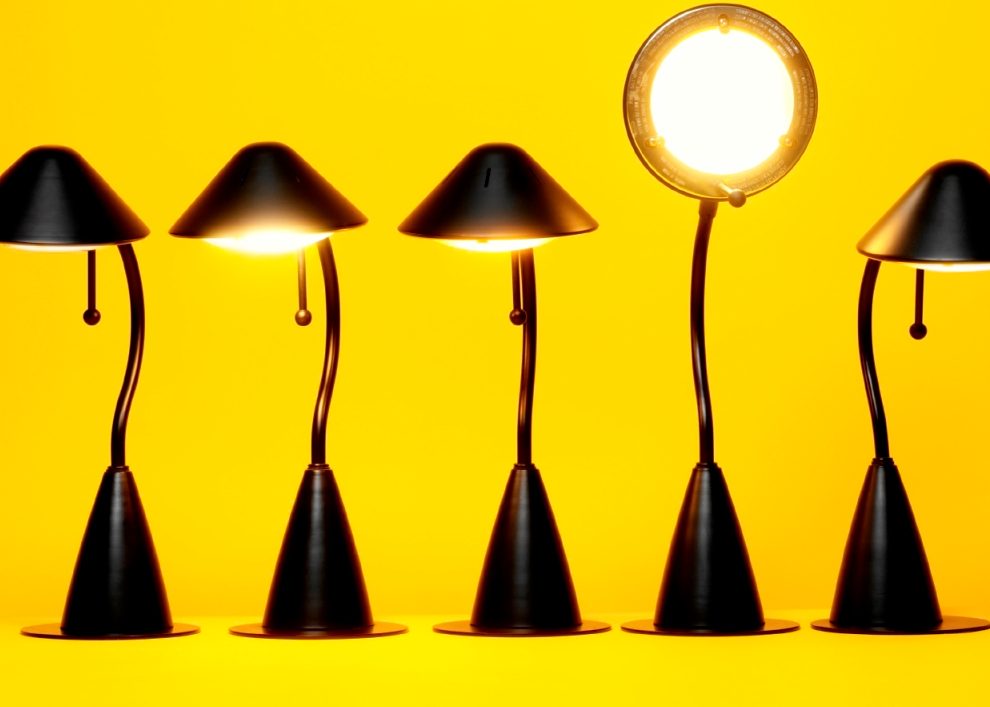 5 desk lamps with the 4th one facing forward on a yellow background