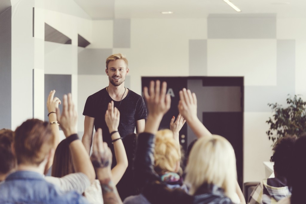 Students raising hands to ask a presenter quetions