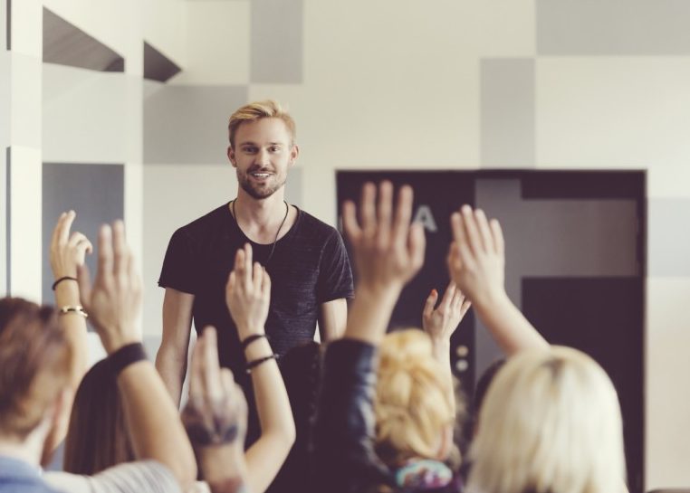 Students raising hands to ask a presenter quetions