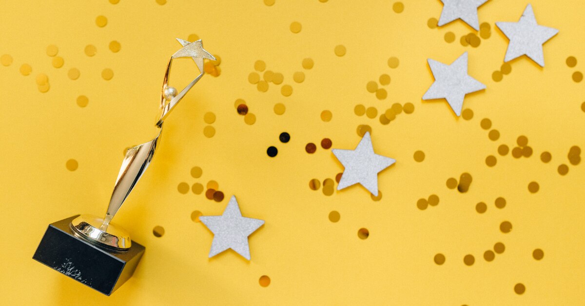 Trophée avec des paillettes et des étoiles éparpillées sur un fond jaune