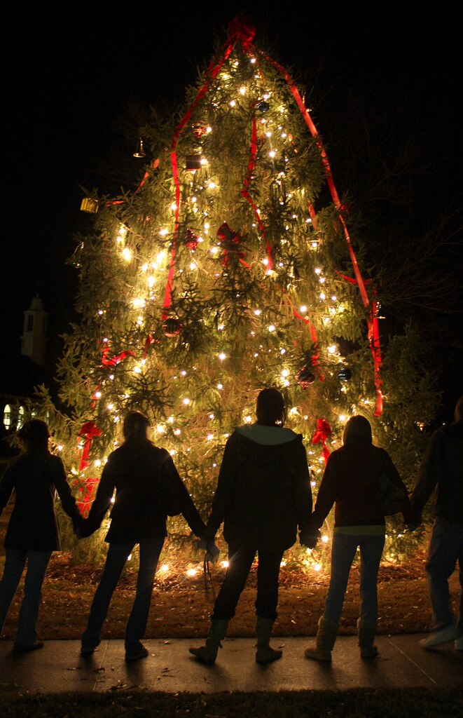 Des gens qui se tiennent la main devant un sapin de Noël