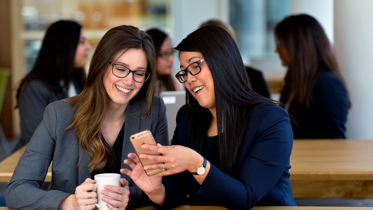 Deux femmes souriant et regardant un téléphone portable