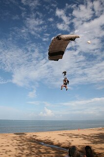 Des gens sur le point d’atterrir sur la plage après avoir fait du parachutisme