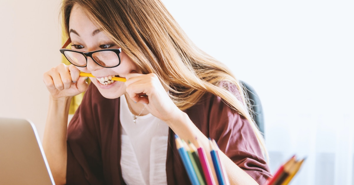 Fille stressée mordant un crayon en regardant un ordinateur portable