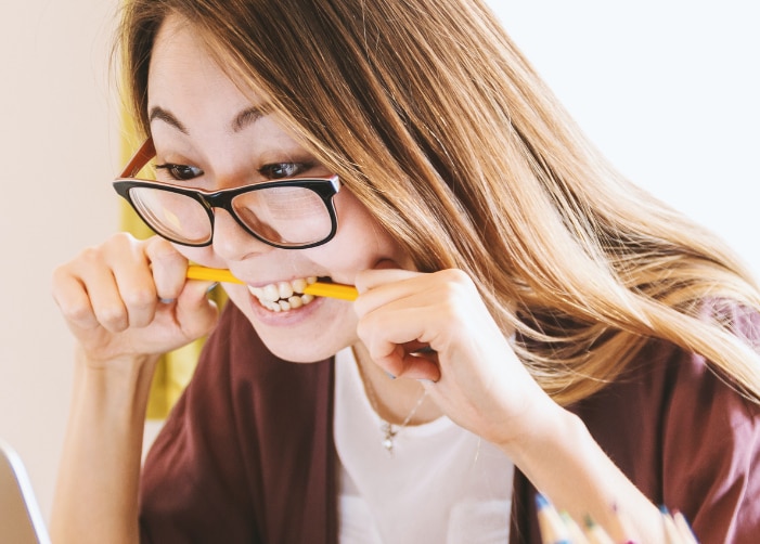 Fille stressée mordant un crayon en regardant un ordinateur portable