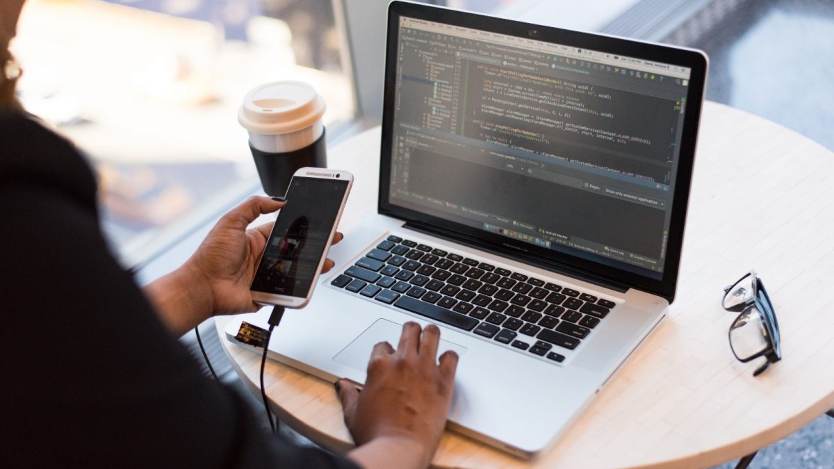 Personne regardant MacBook tout en utilisant son téléphone portable