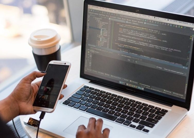 Personne regardant MacBook tout en utilisant son téléphone portable