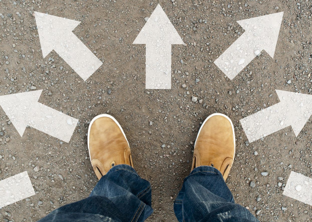Pieds sur le trottoir entourés de flèches pointant dans différentes directions