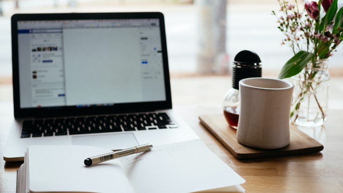 Ouvrez l'ordinateur portable et le bloc-notes avec un stylo et une tasse à café sur le bureau