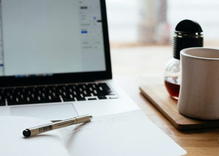 Ouvrez l'ordinateur portable et le bloc-notes avec un stylo et une tasse à café sur le bureau