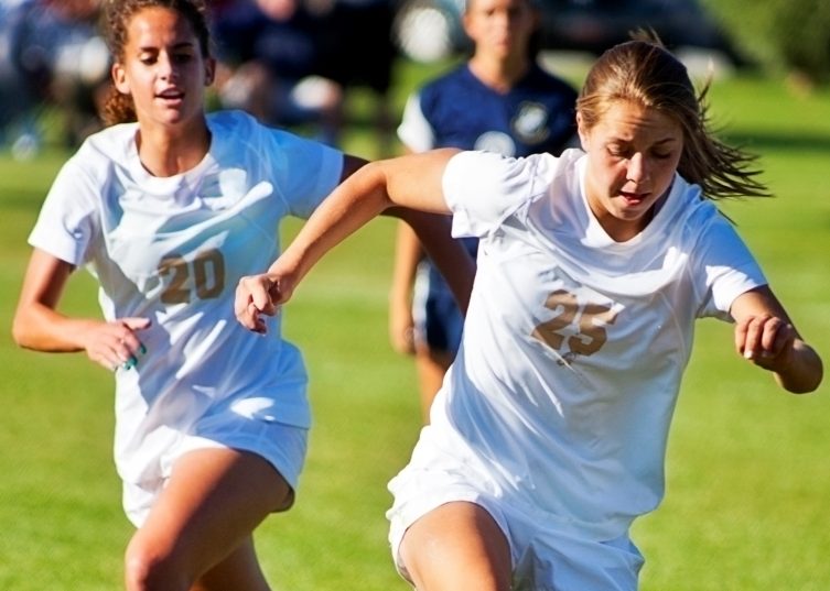 Des filles jouant au football en uniforme blanc