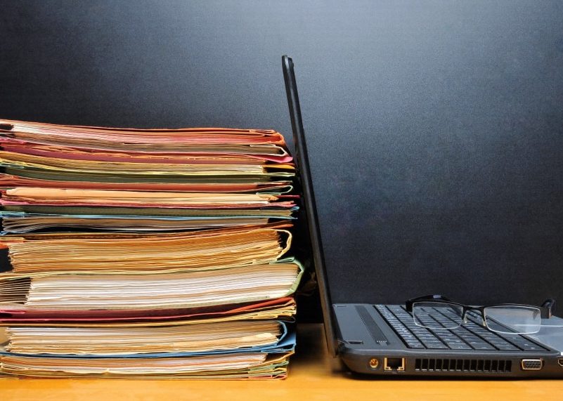 Ordinateur portable avec lunettes sur le clavier à côté de la pile de dossiers