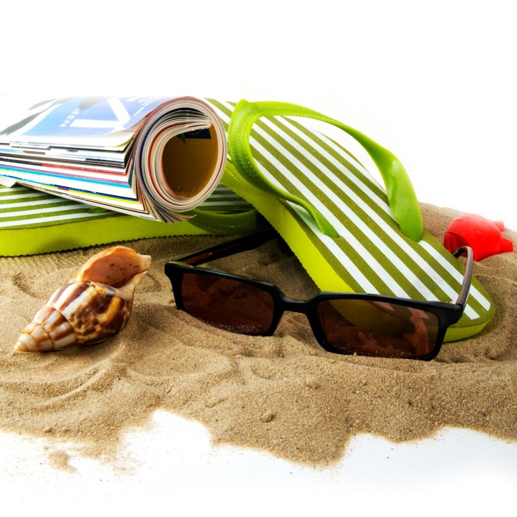 Lunettes de soleil, magazine, sandales et coquillage sur la plage