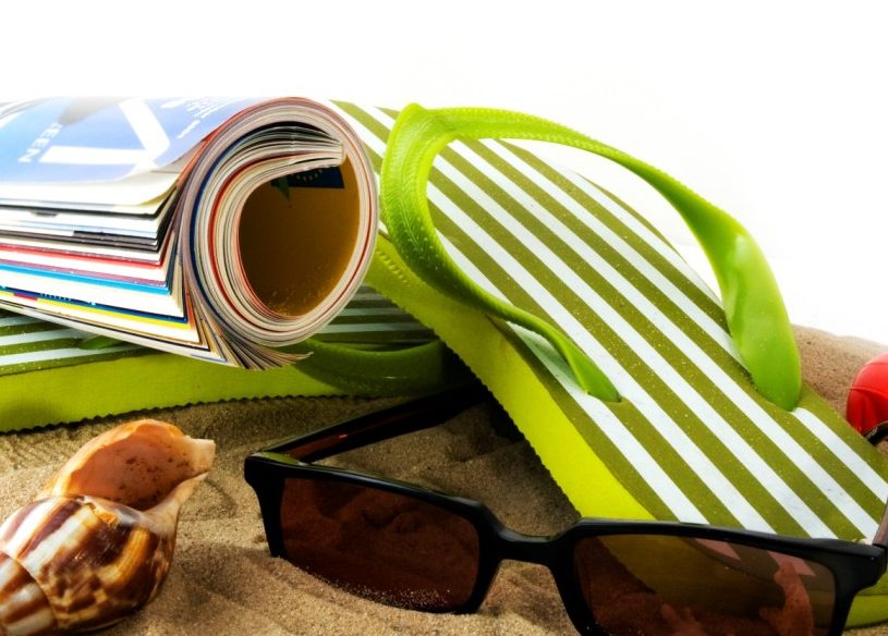 Lunettes de soleil, magazine, sandales et coquillage sur la plage