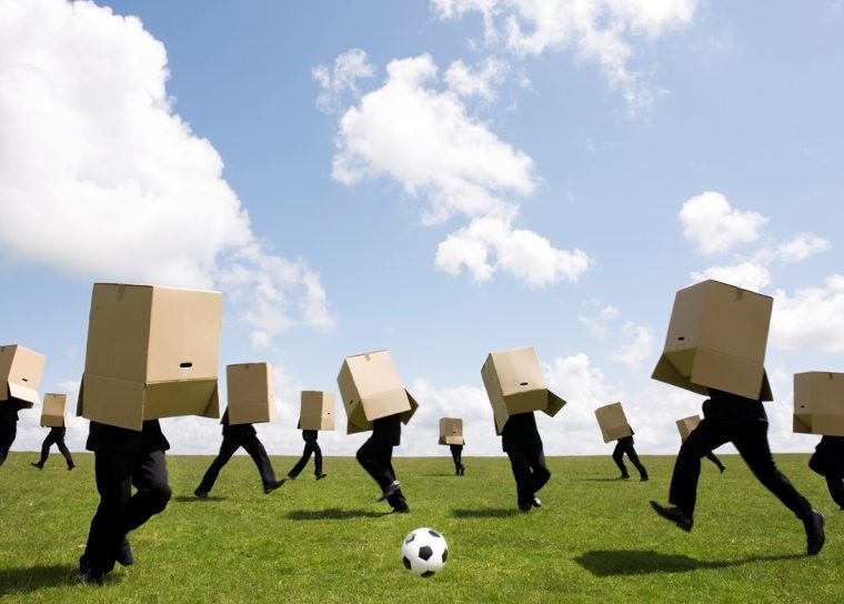 Des gens qui jouent au football avec des boîtes en carton au-dessus de la tête