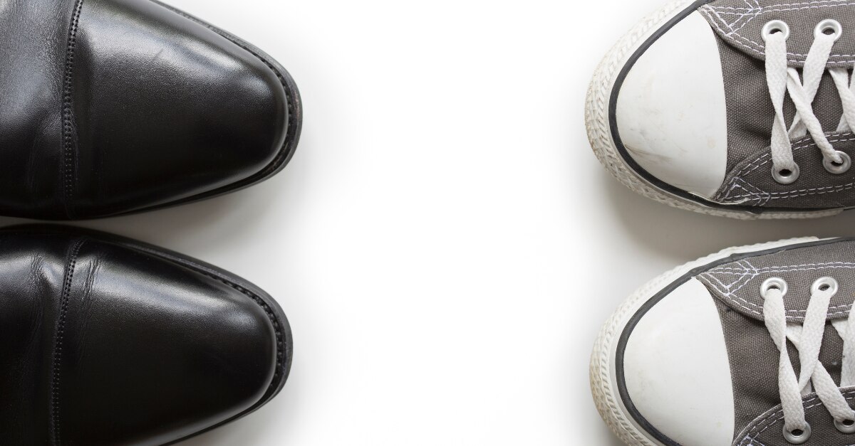Paire de chaussures habillées noires face à une paire de Converse grise