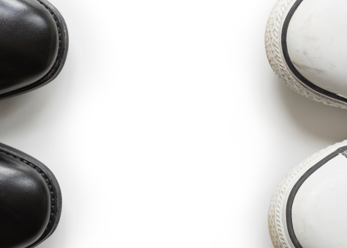 Paire de chaussures habillées noires face à une paire de Converse grise