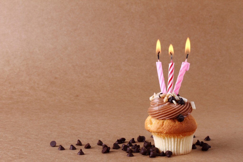Cupcake avec trois bougies allumées entouré de pépites de chocolat