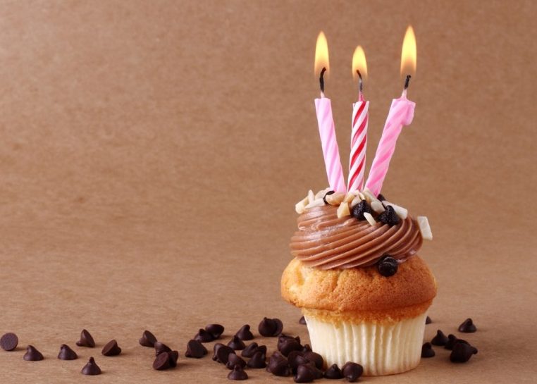 Cupcake avec trois bougies allumées entouré de pépites de chocolat