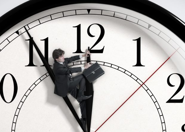 Un homme avec une mallette qui monte sur l'aiguille des heures d'une horloge