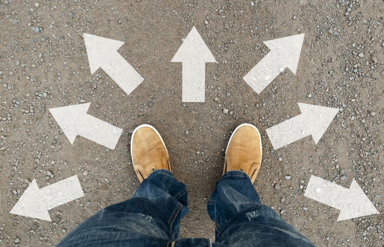 Pieds avec des chaussures bronzées sur le trottoir avec des flèches pointant dans plusieurs directions