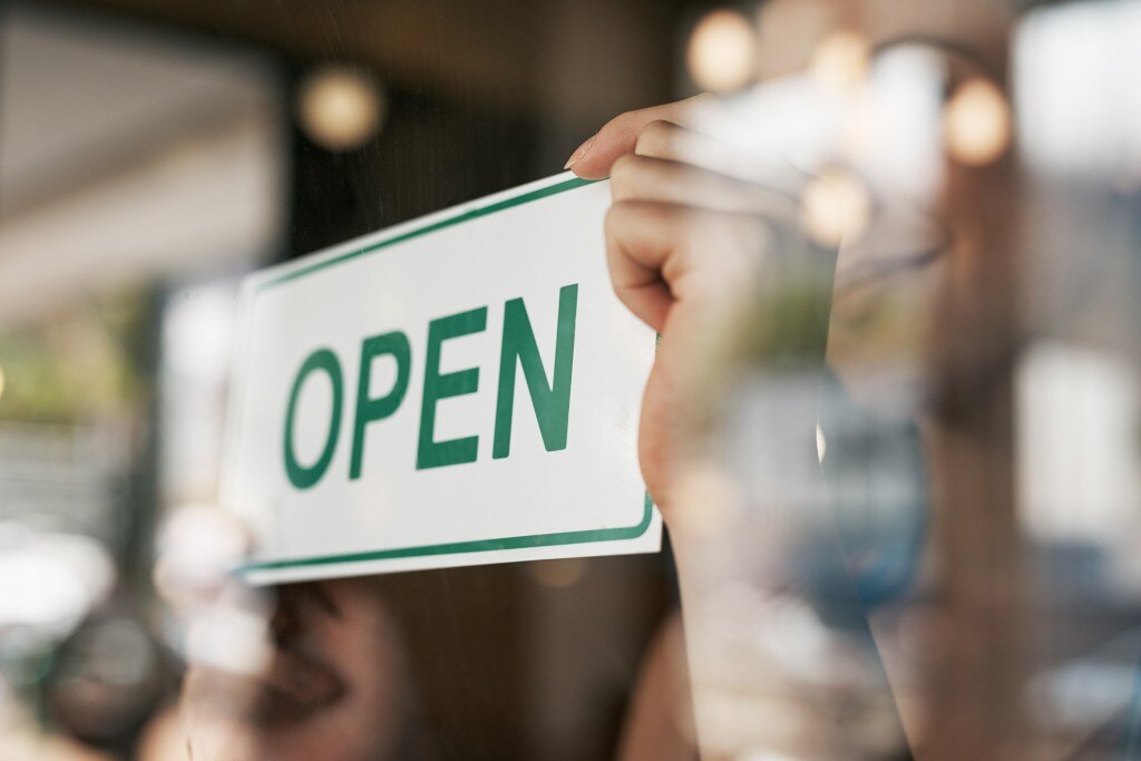 Mains retournant le panneau « OUVERT » vert et blanc