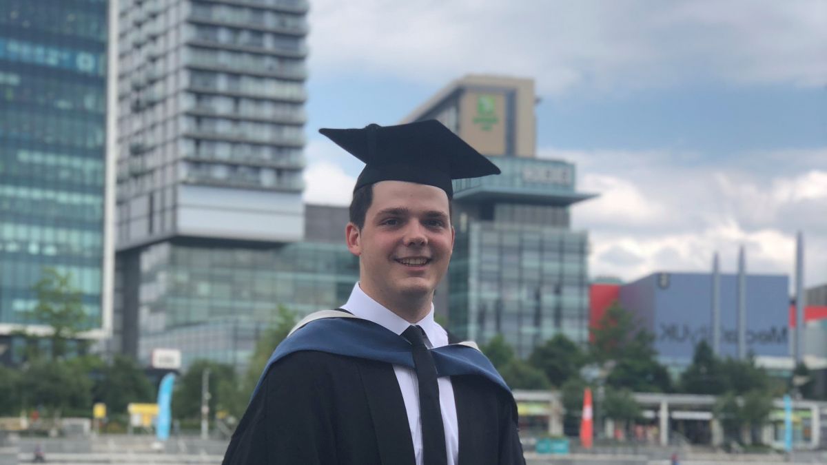 Tommy en casquette et robe de remise de diplôme devant des gratte-ciels