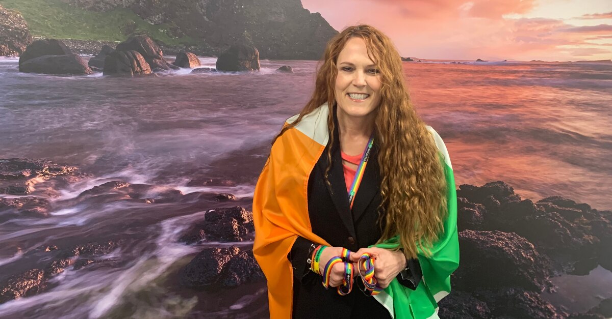 Leslee avec le drapeau irlandais autour de ses épaules face à l'océan
