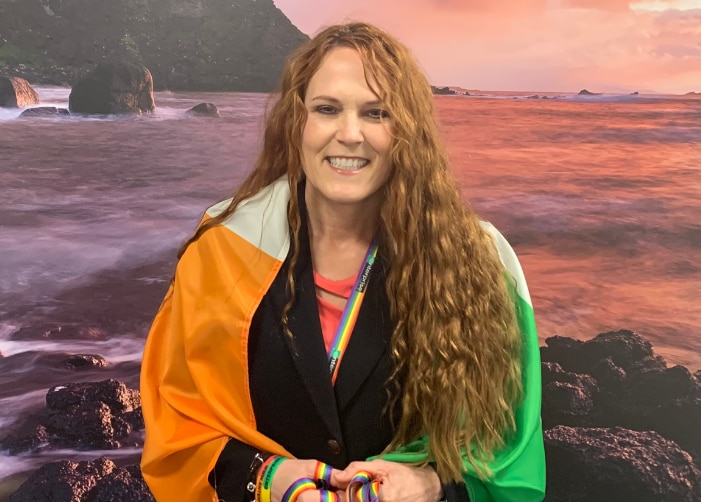 Leslee avec le drapeau irlandais autour de ses épaules face à l'océan