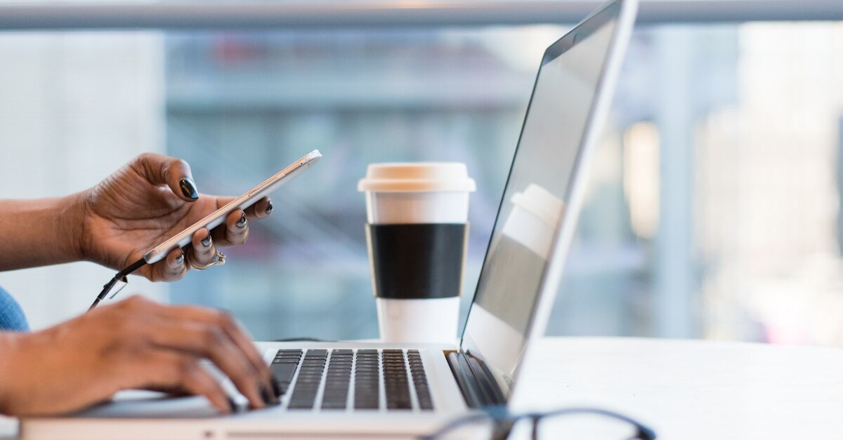 Tenir un téléphone et taper sur un MacBook dans un café