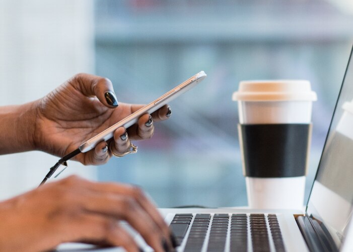 Tenir un téléphone et taper sur un MacBook dans un café