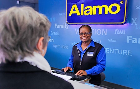 Femal Alamo employee helps customer at computer