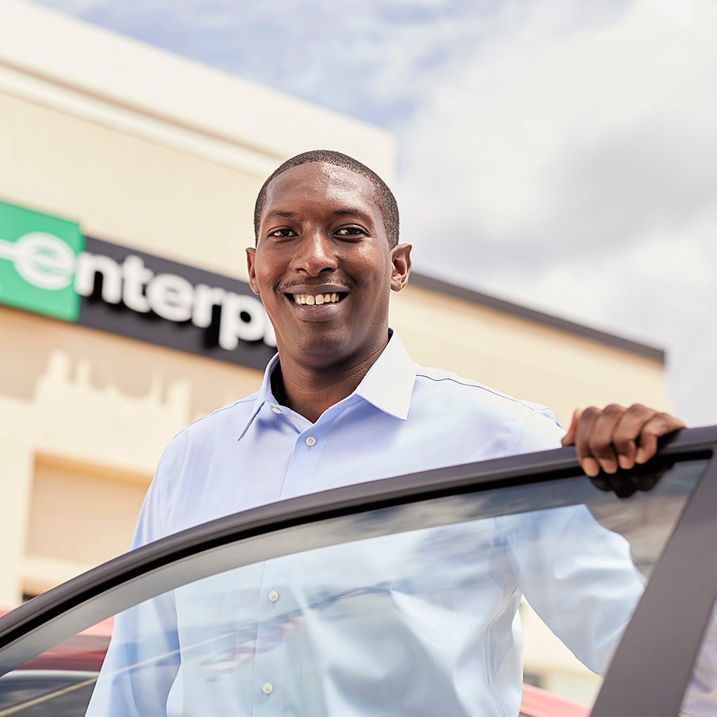Membre d’équipe se penchant par-dessus une portière de voiture ouverte en souriant 
