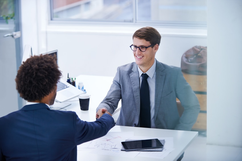deux hommes serrant la main sur un bureau